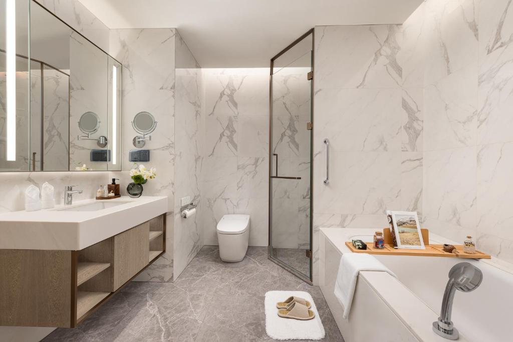 a bathroom with a tub and a toilet and a sink at Somerset QPlex Shenzhen in Shenzhen