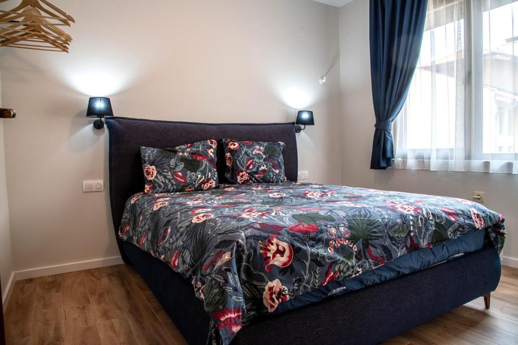 a bedroom with a black bed with a floral bedspread at Bansko Ski Apartment in Bansko