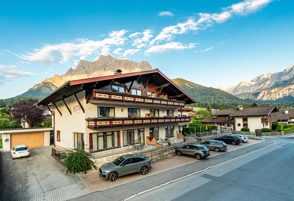 a building with cars parked in front of a mountain at Rustika - Appartements & Spa in Ehrwald