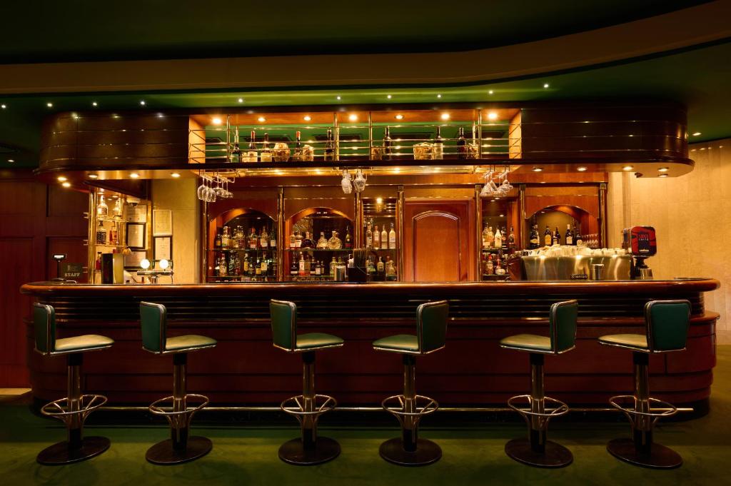 a bar with green bar stools in front of it at Grand Hotel Bucharest in Bucharest