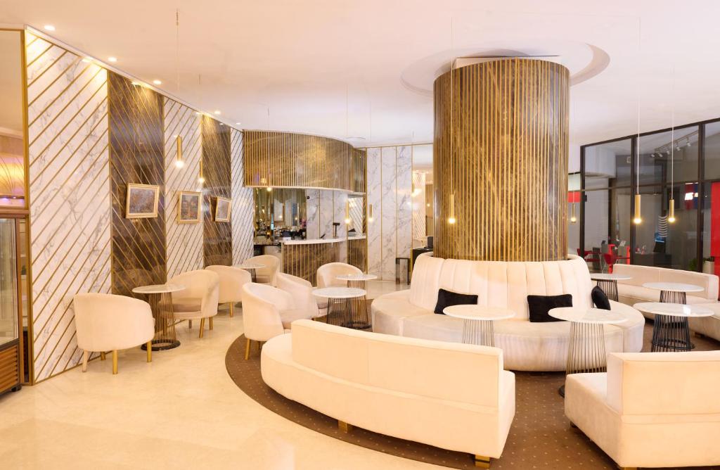 a lobby with white furniture and tables and chairs at Grand Hotel Bucharest in Bucharest