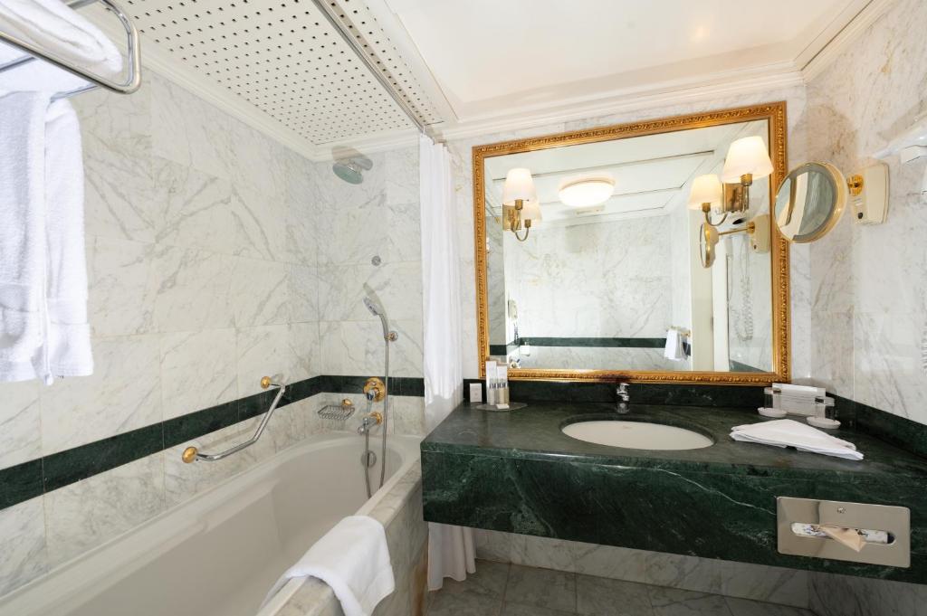 a bathroom with a sink and a tub and a mirror at Grand Hotel Bucharest in Bucharest