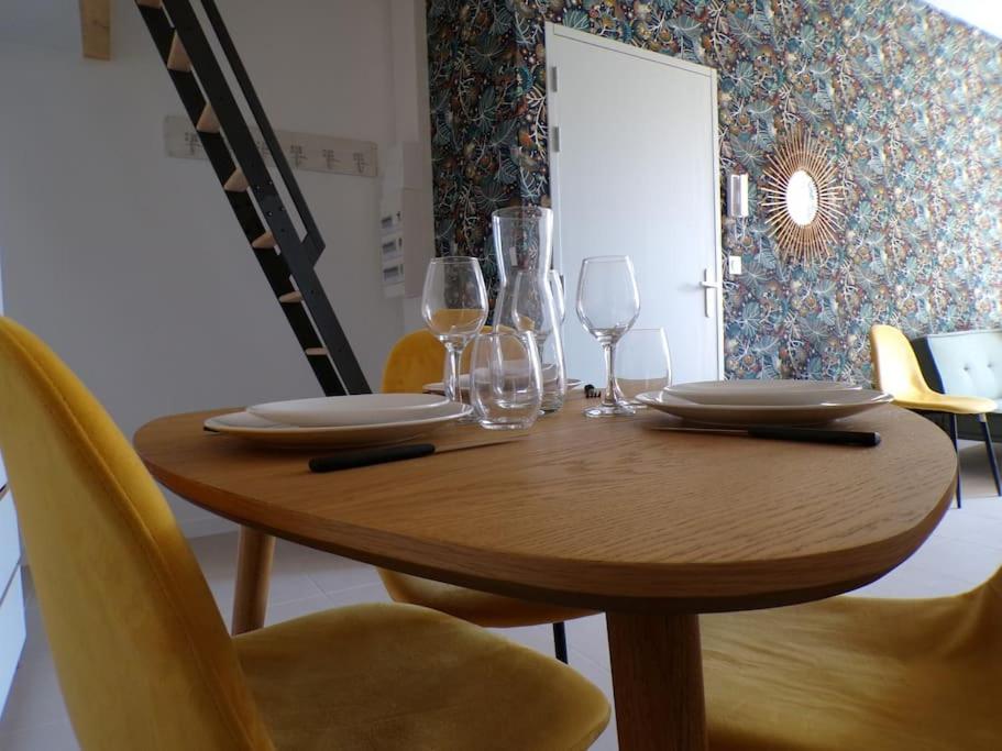 a wooden table with plates and wine glasses on it at L'atypique studio 1 à 3 voyageurs in Bazas