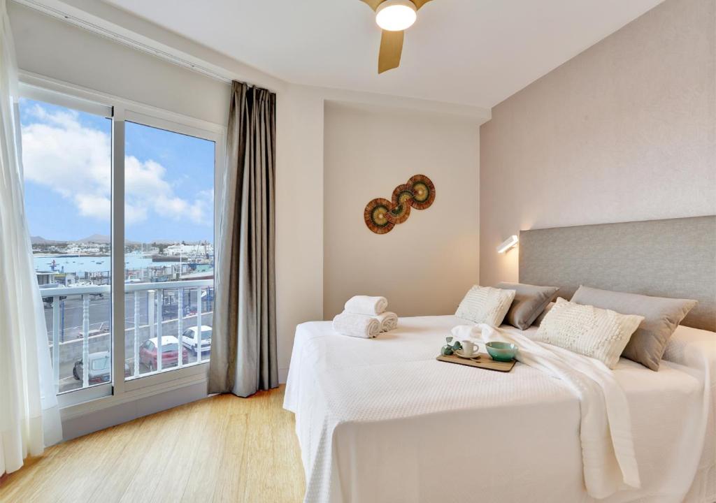 a bedroom with a white bed with a large window at Silvic Jable in Corralejo