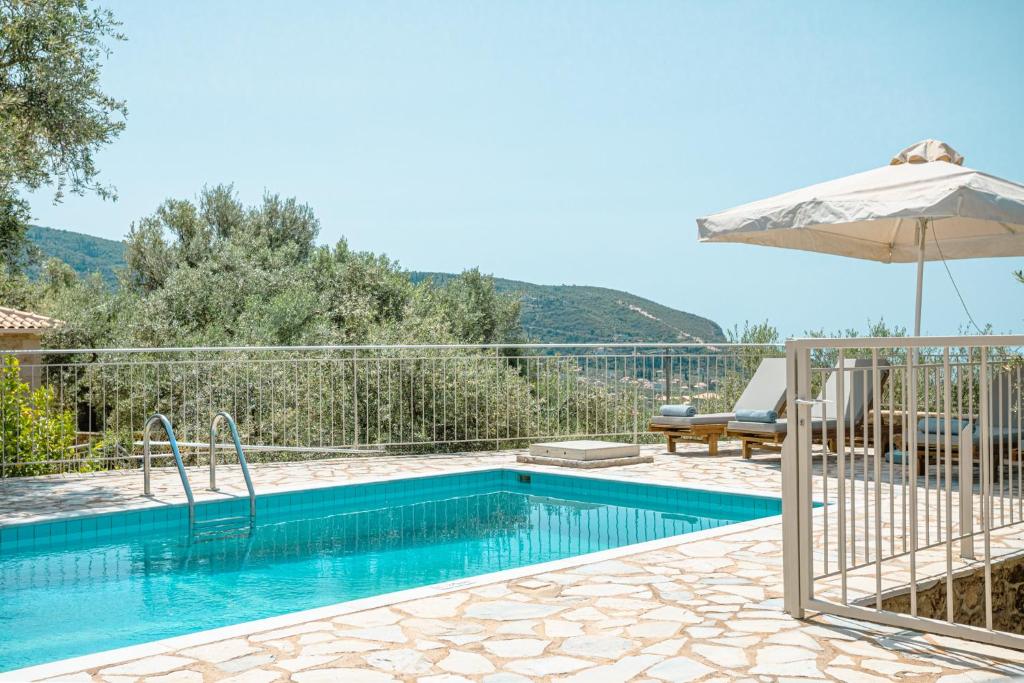 a swimming pool with an umbrella next to a house at Elia Villas in Riglia