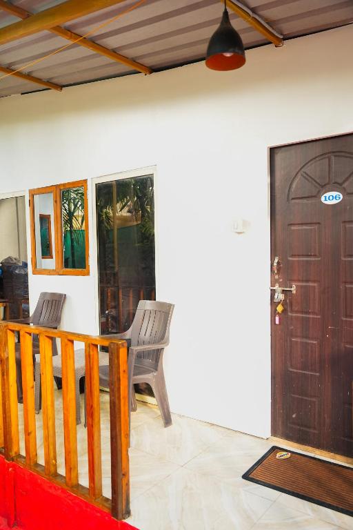 a room with two chairs and a wooden door at Palolem Cottages in Palolem