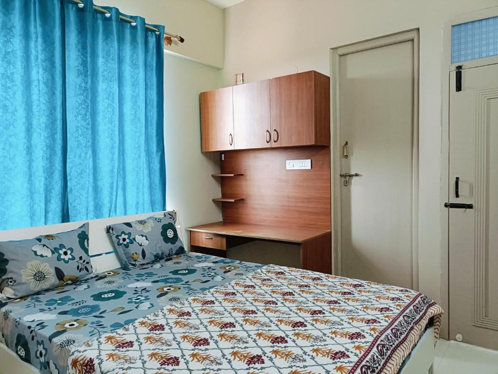 a bedroom with a bed and a desk with a blue curtain at 2BHK Flat by SR Renton Comfort Homestay Mysore @ Vijayanagar 2nd stage Mysore in Mysore