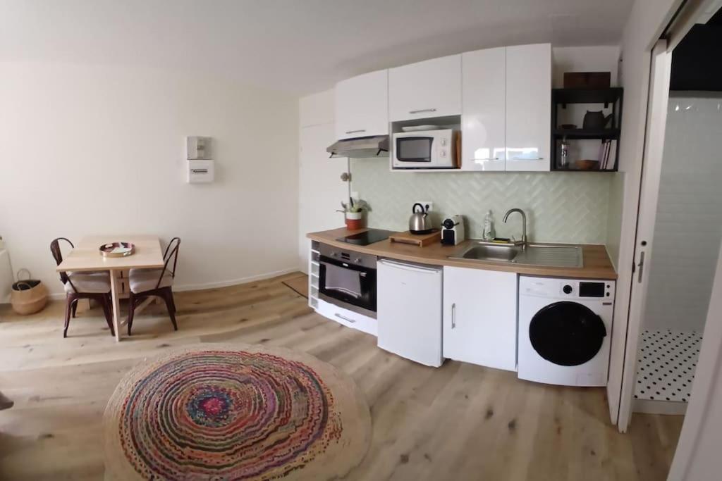 une cuisine avec des placards blancs et une table avec un tapis dans l'établissement Horizon Royal, à Sète