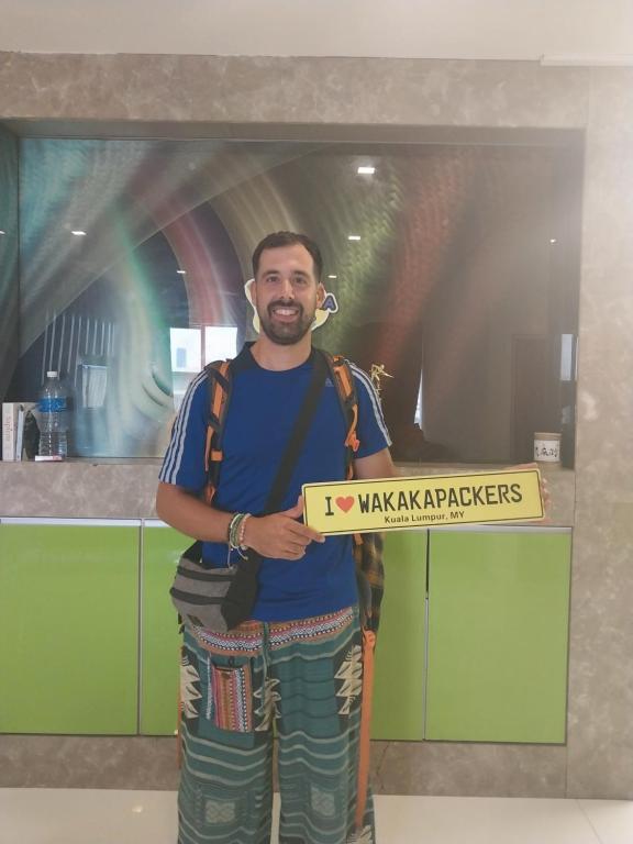 a man holding a pizza box in a kitchen at WakakaPackers in Kuala Lumpur