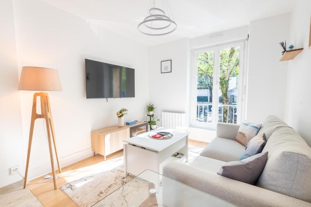 un salon avec un canapé et une télévision dans l'établissement PREMIUM T2 neuf 1er étage ultra Centre Lorient par Groom, à Lorient