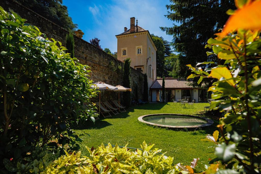 a garden with a building and a pond in the yard at Lyon Country House - Suites & Tour de Garde in Caluire-et-Cuire