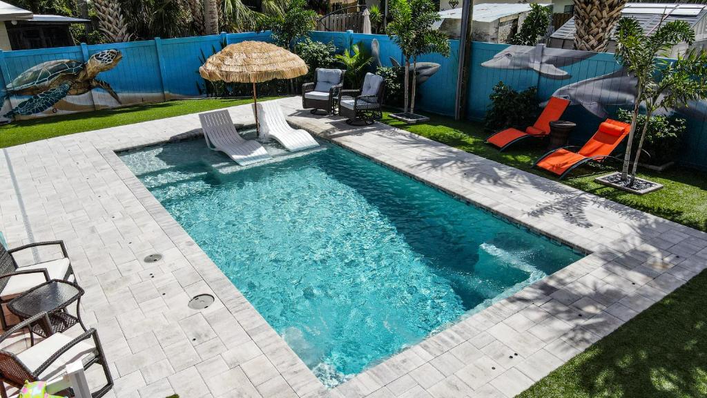 a swimming pool with chairs and an umbrella at Private saltwater pool, 386 steps to ocean, amazing rocket launch view! in Cocoa Beach