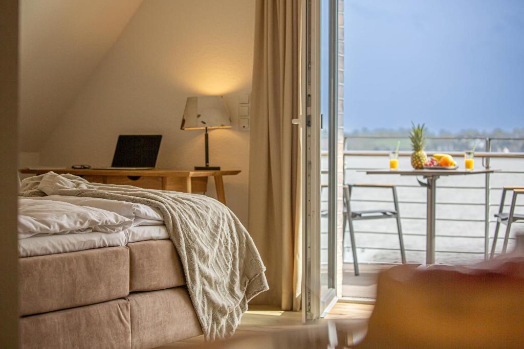 ein Schlafzimmer mit einem Bett und einem Tisch mit einem Laptop in der Unterkunft Deluxe Studio-Apartment "Wiking-Koje 10" direkt an der Schlei in Schleswig