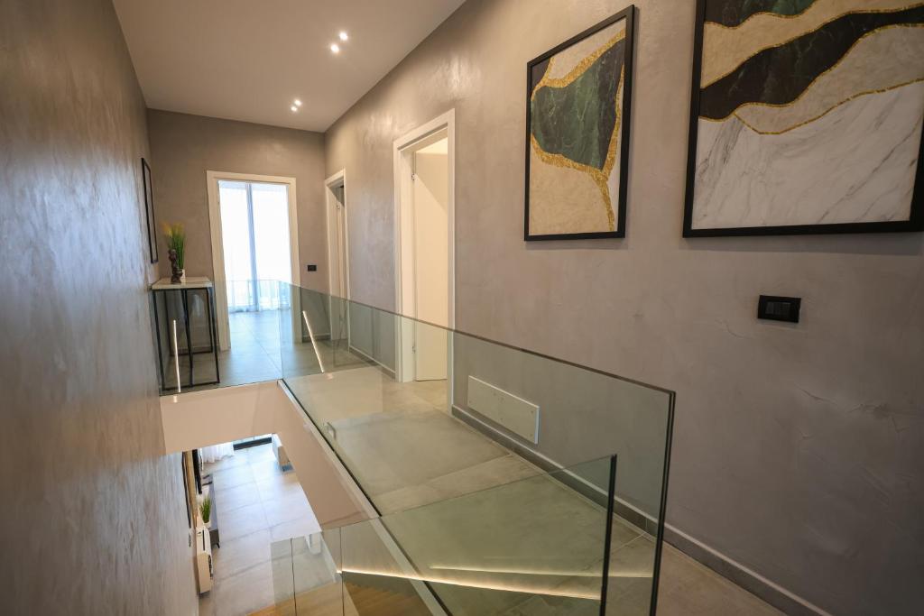 a hallway with a glass staircase and paintings on the wall at Green Coast Resort V94 in Palasë
