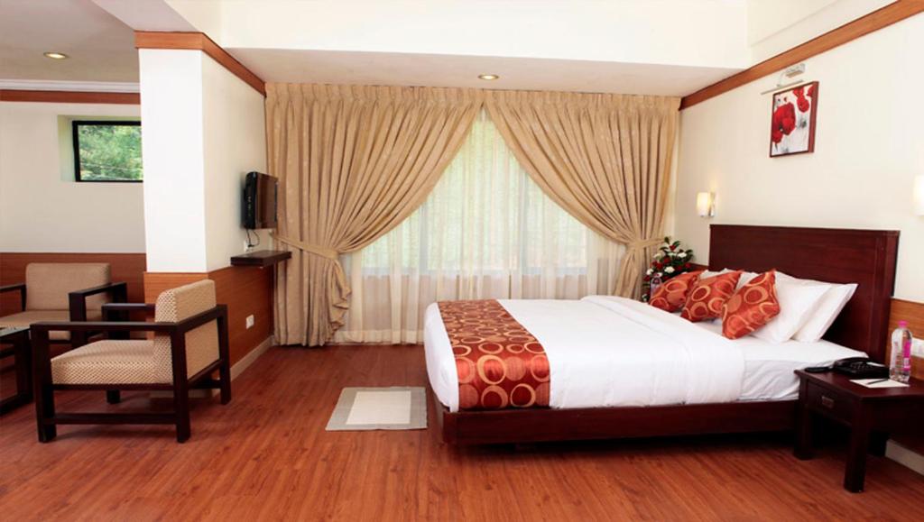 a bedroom with a bed and a desk and a window at Clouds Valley Hotel in Munnar