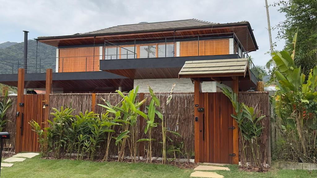 a house with a wooden fence in front of it at Casa Fiji - Suites Luxo - Praia de Itamambuca - Ao lado da praia in Ubatuba