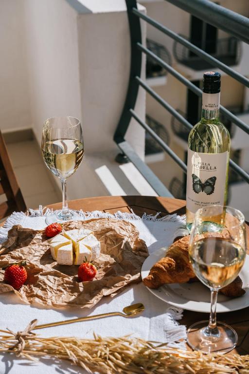 a bottle of wine and a plate of cheese and wine glasses at Sunny 2 BR Aptm with Garden Fast WiFi Walk to Seafront in Il-Gżira