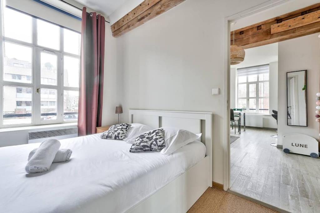 une chambre blanche avec un grand lit blanc avec des oreillers dans l'établissement Appartement lumineux et calme parking gratuit, à Lille