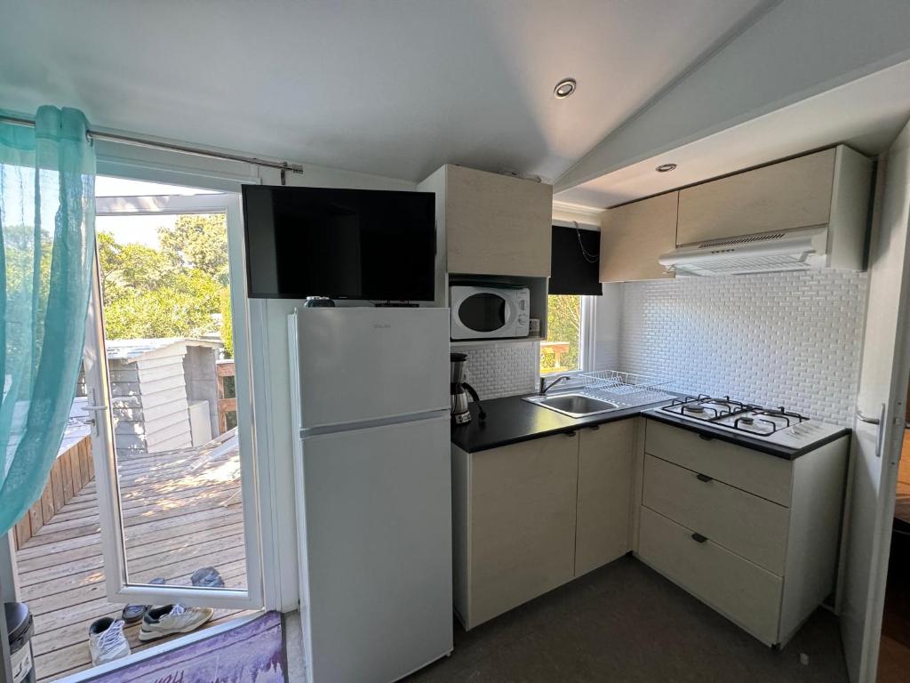 Il dispose d'un balcon et d'une petite cuisine équipée d'un réfrigérateur blanc. dans l'établissement Chez Flo Mobil-Home H13, à Gassin