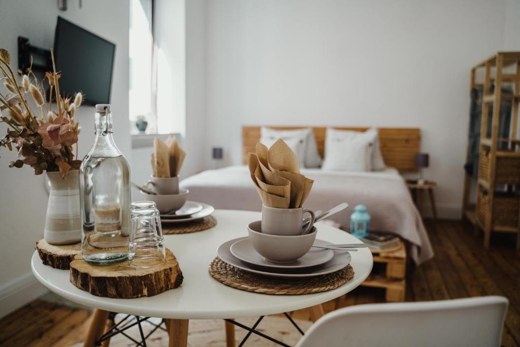 a room with a bed and a table with cups and plates at I Gemütliches 1-Zimmer-Apartment & eigenes Bad I in Neuendorf