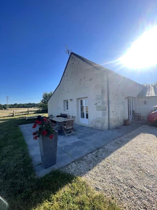 un petit bâtiment blanc avec une table dans une cour dans l'établissement Le Chèvrefeuille, à Cerelles