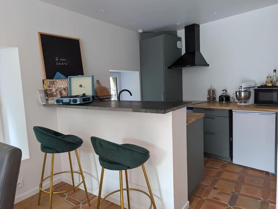 a kitchen with two green stools at a counter at Maison de campagne au bord du ruisseau-5mn mer in Lamballe Armor