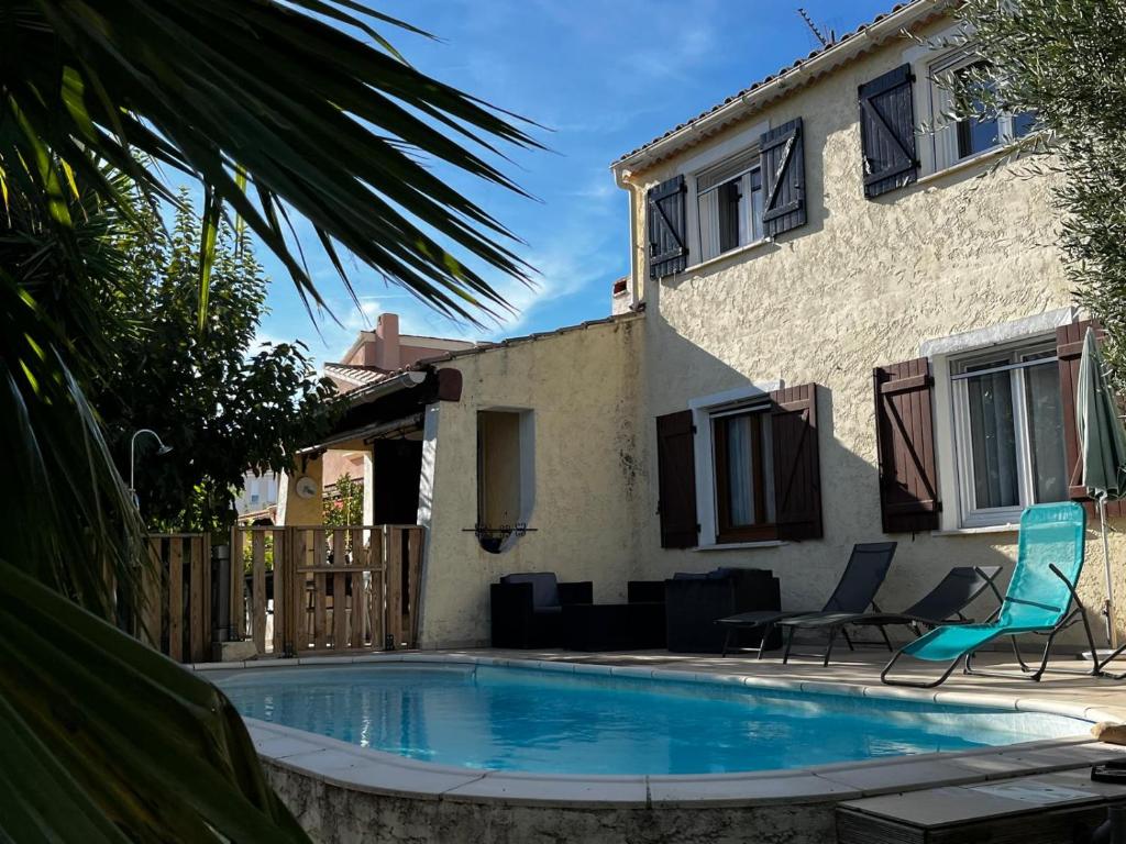 une piscine avec deux chaises et une maison dans l'établissement Maison familiale classée 3 Etoile - Clim & Piscine privée -, à La Farlède