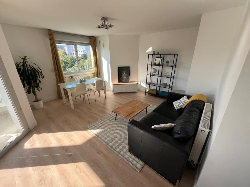 un salon avec un canapé noir et une table dans l'établissement Appartement Cosy Lyon - Confluence, à Lyon