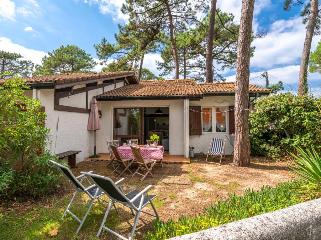 une petite maison blanche avec des chaises et une table dans l'établissement Apartment Hameau du courant-1 by Interhome, à Mimizan