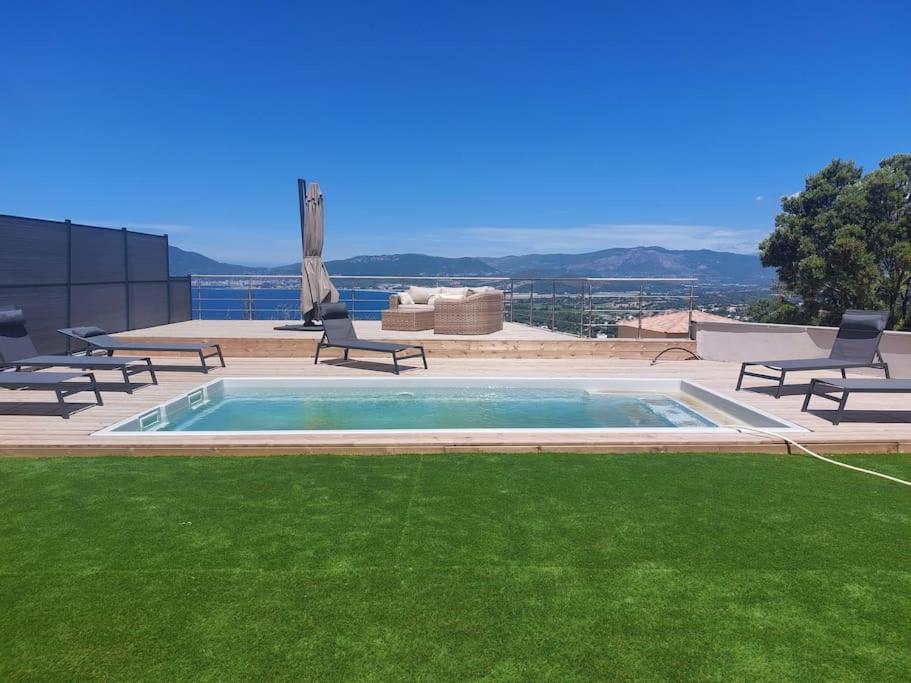 - une piscine avec des chaises et une pelouse dans l'établissement Bella Vita Garancia Grand T3 Neuf avec piscine à Porticcio, à Grosseto-Prugna