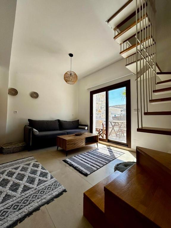 a living room with a black couch and a staircase at Stelios House in Pserimos in Psérimos