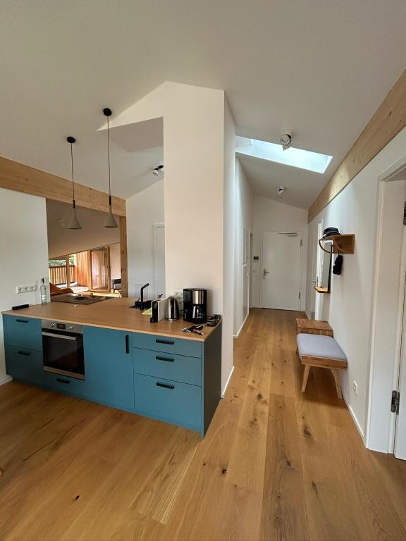 a large kitchen with blue cabinets and a wooden floor at Apartment Virgo7 - stylisch, neuerbaut und topausgestattet in Fischbachau