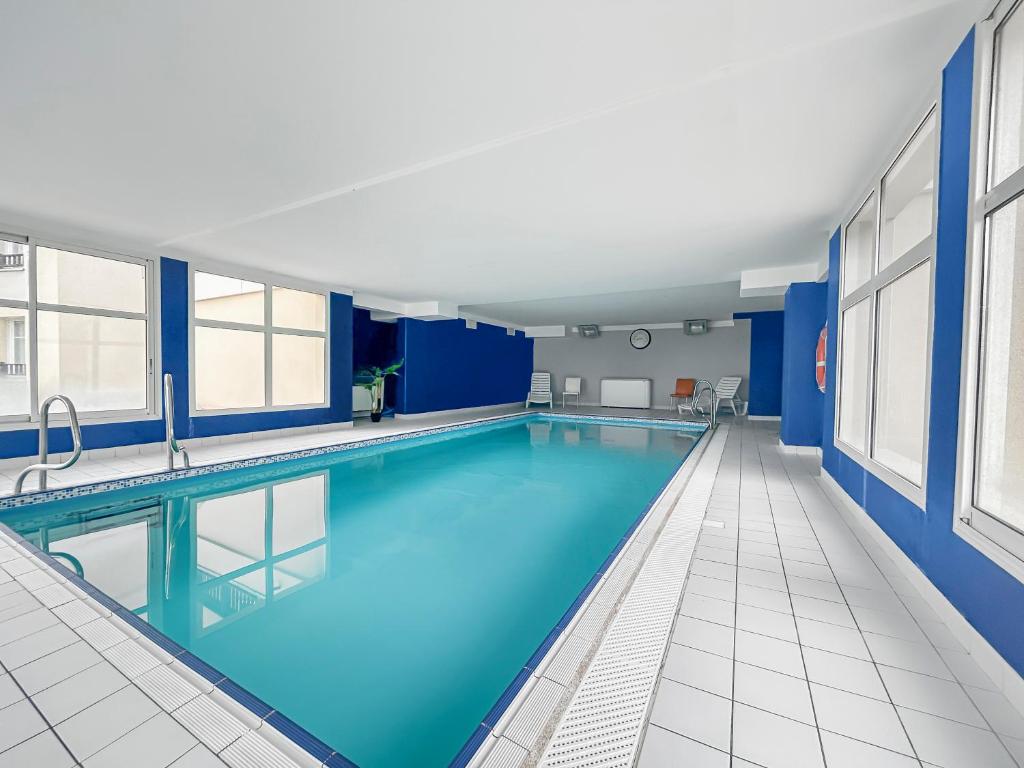 a large swimming pool in a building with blue walls and windows at Chez Marianne Résidence Piscine Sauna in Levernois