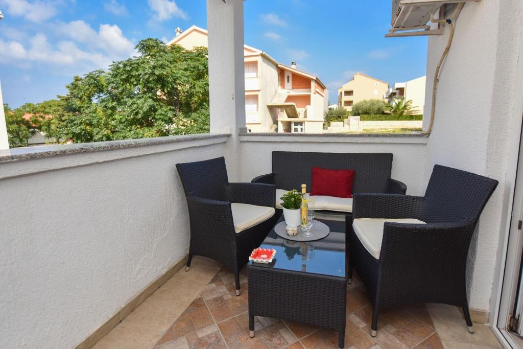 balkon z krzesłami i stołem z czerwoną poduszką w obiekcie Apartment Kety w Novalji
