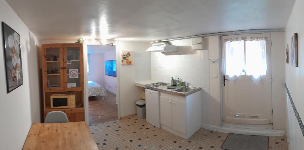 Elle comprend une petite cuisine blanche avec un évier et une fenêtre. dans l'établissement Studio indépendant avec jardin, à Saint-Cyr-sur-Loire