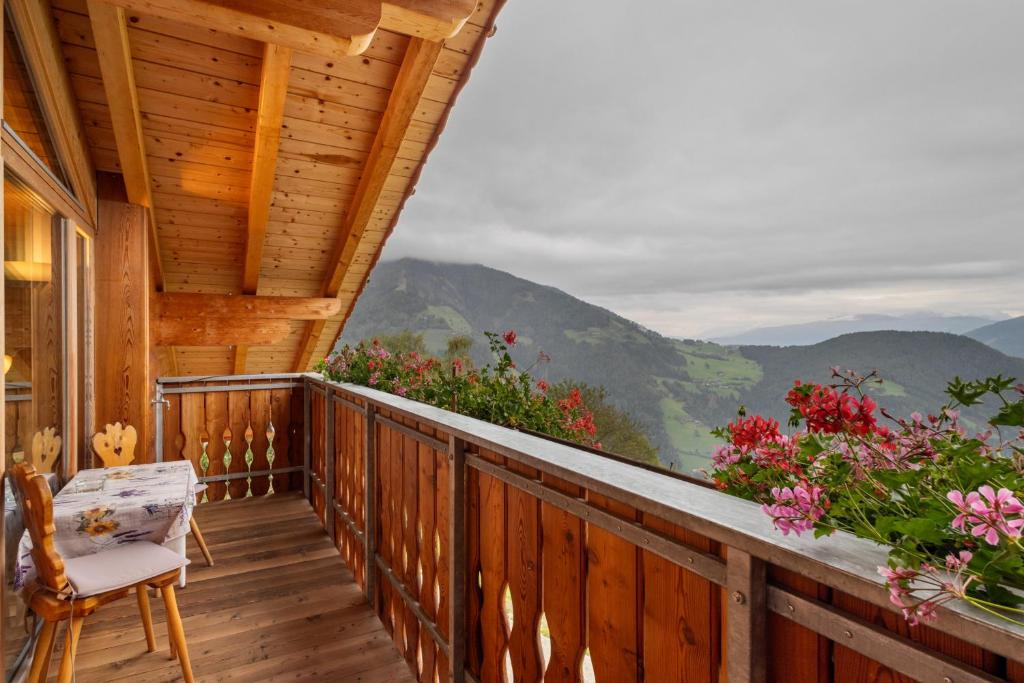 een veranda van een hut met een stoel en bloemen bij Oberhof Apt Panorama in Vallarga