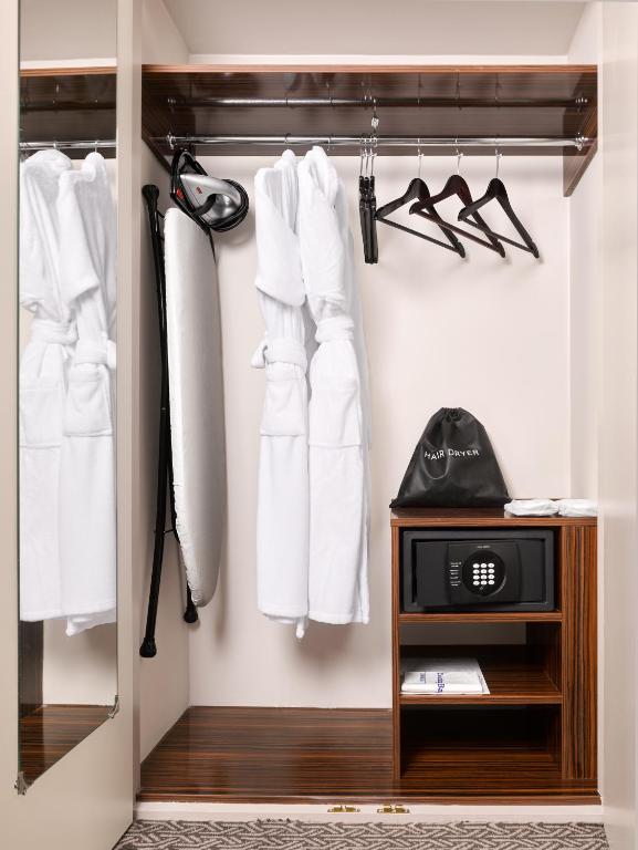 a closet with white clothes and a clock in it at Strand Palace in London