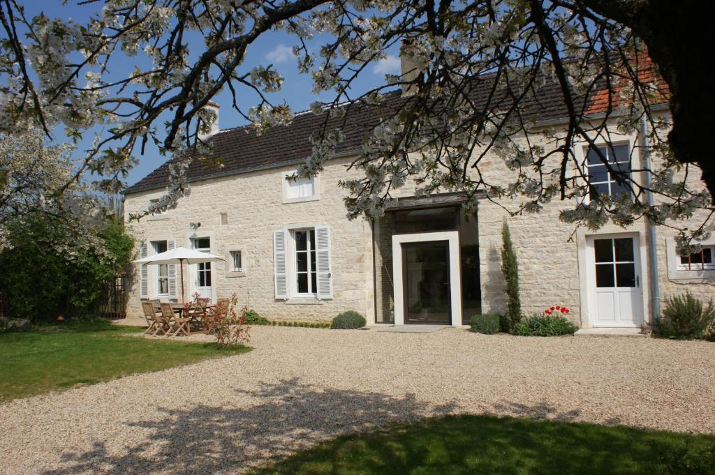 ein weißes Backsteinhaus mit einem Tisch und Stühlen davor in der Unterkunft Gîte La Maison De Lucien in Meursault