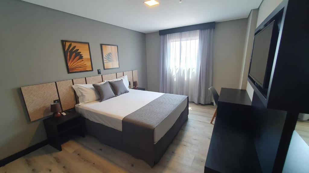 a bedroom with a bed and a flat screen tv at Tulip Inn Bauru in Bauru