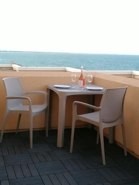 une table avec deux chaises, une bouteille et deux verres dans l'établissement Horizon, à Collioure
