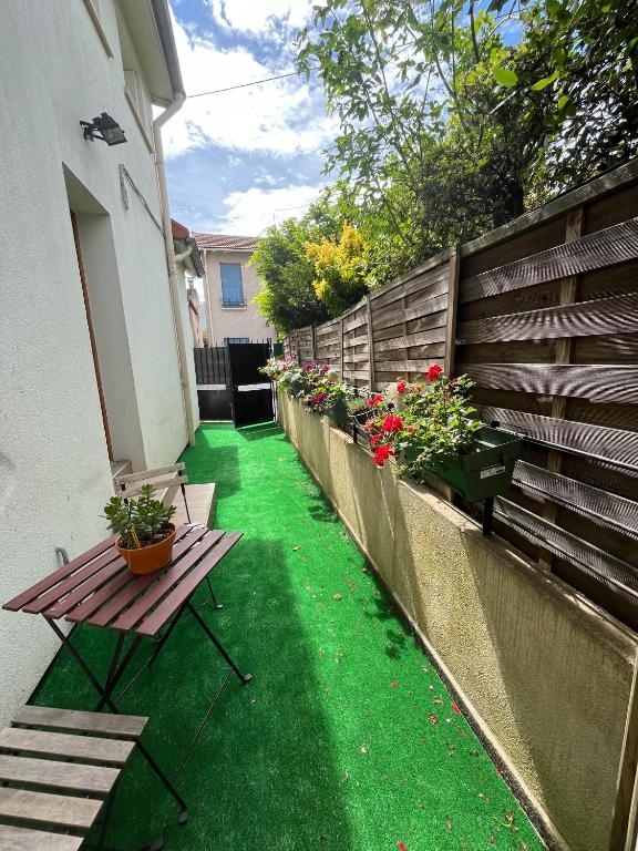une terrasse avec un banc, des fleurs et une clôture dans l'établissement Maison proche de Paris, à Vanves