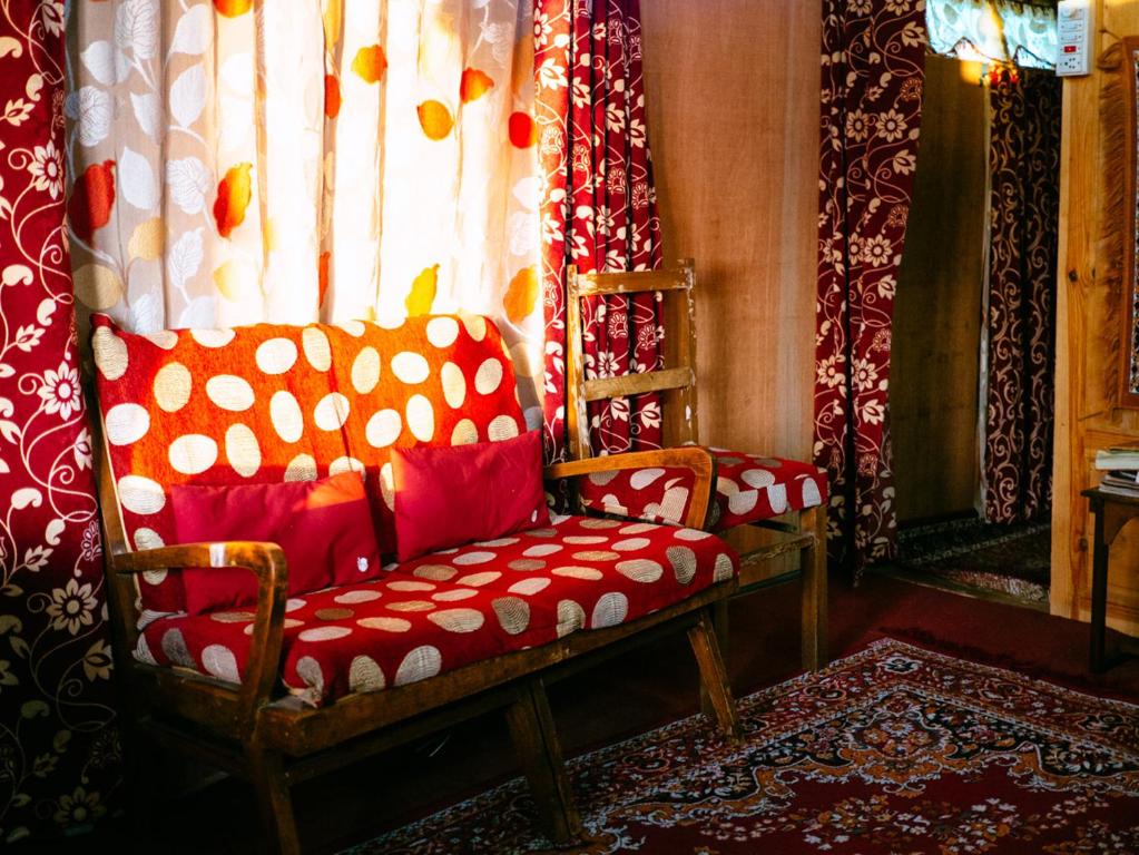 uma sala de estar com uma cadeira vermelha e uma janela em Veena Palace Group Of Houseboats em Srinagar