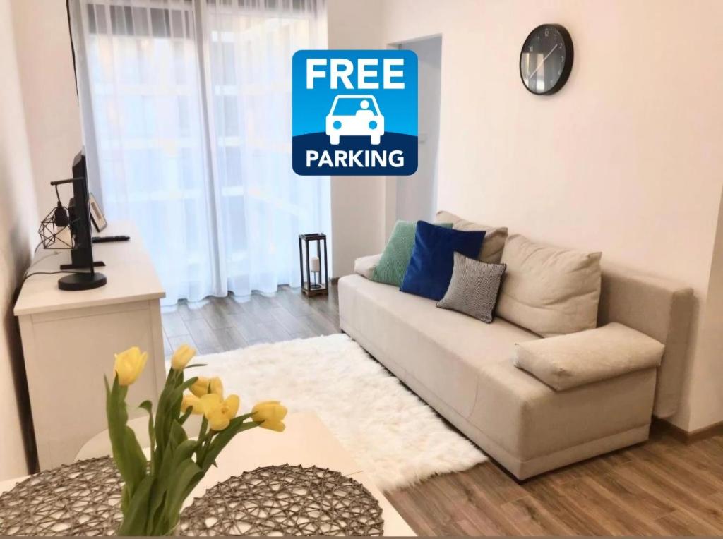 a living room with a white couch and a free parking sign at Apartament Active Moon in Lublin