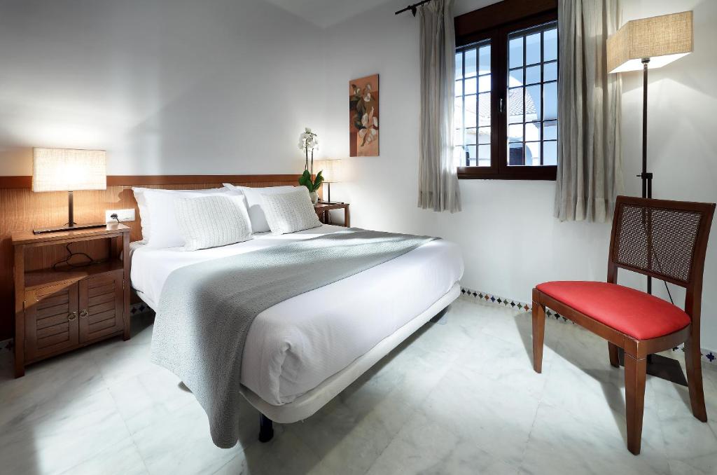 - une chambre avec un grand lit et une chaise rouge dans l'établissement Apartamentos Patios de Alcántara, à Cordoue