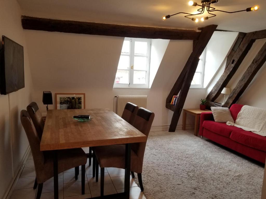 a dining room with a table and a red couch at Best of Chartres one bedroom city center and view on the Cathedral in Chartres