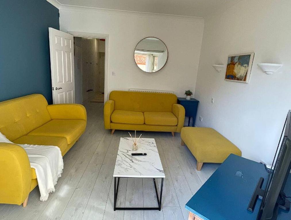 a living room with two yellow couches and a table at Queen Anne Court with FREE PARKING By Prescott Apartments in Abingdon