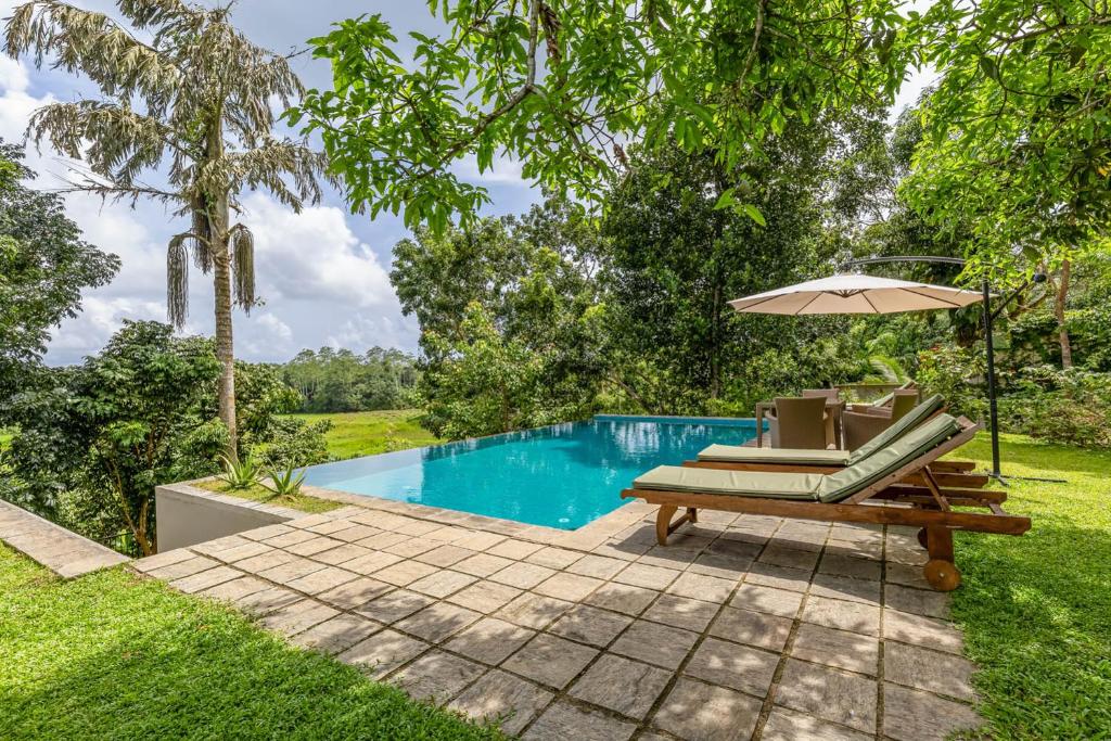 a patio with a bench and an umbrella next to a pool at Samalanka Boutique Hotel in Habaraduwa Central
