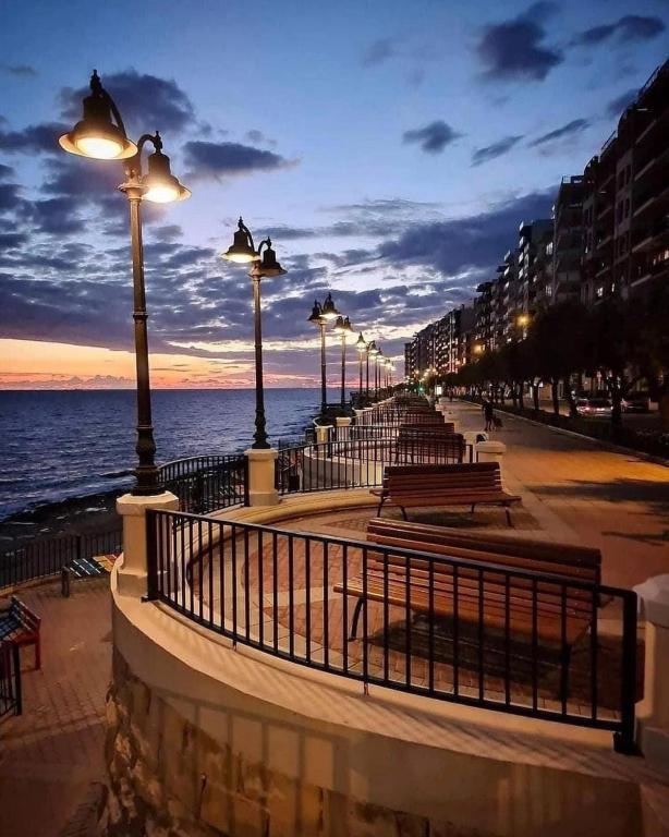 a street with benches and street lights on the beach at Room in Beautiful, Spacious Maltese Maisonette in St. Julianʼs