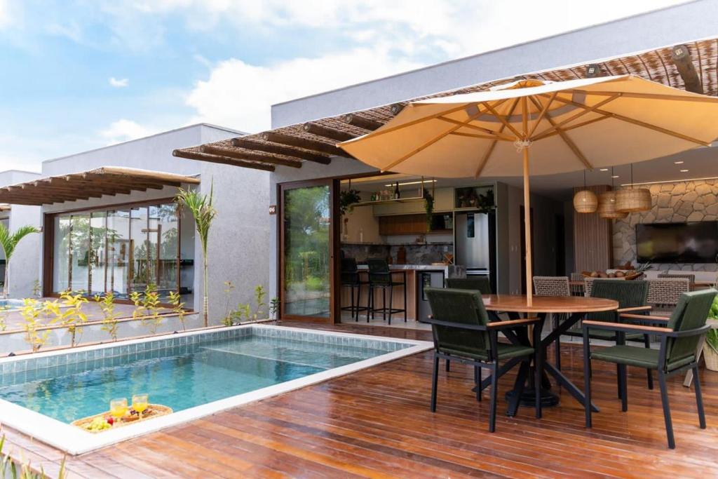 une maison avec une piscine et une table avec des chaises et un parasol dans l'établissement Casa barra grande Maraú, à Marau