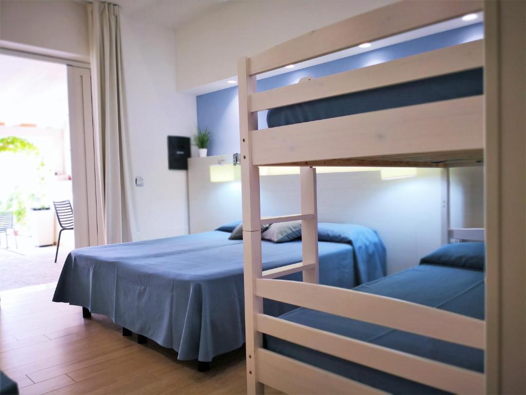 a bedroom with a bunk bed with a blue bedspread at Hotel Perla Gaia in San Vito lo Capo
